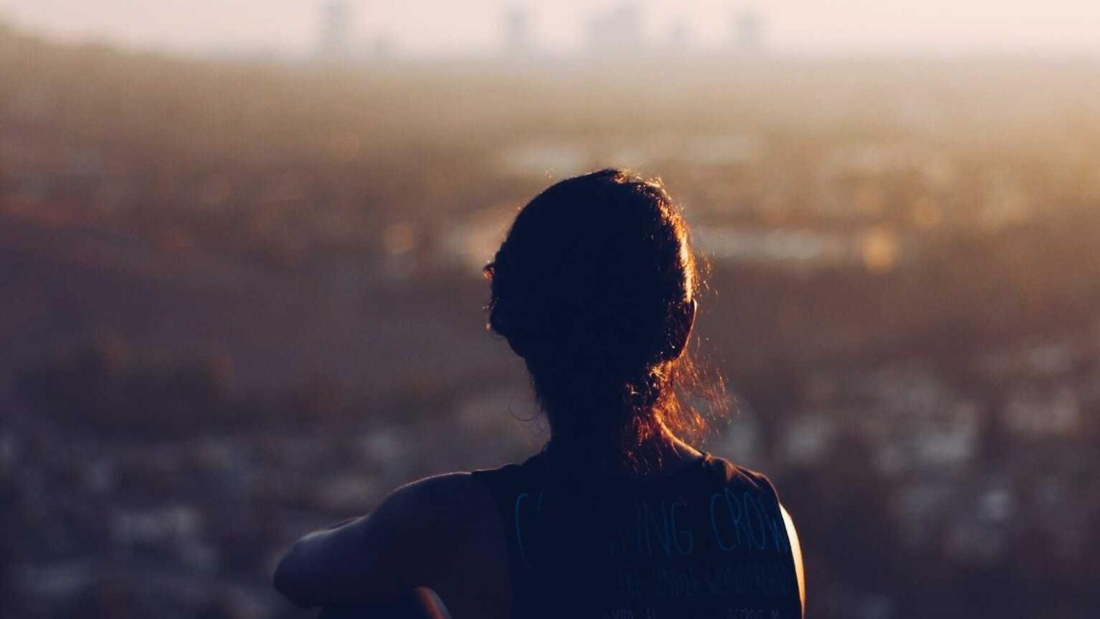 Person blickt über eine Stadt im Abendlicht