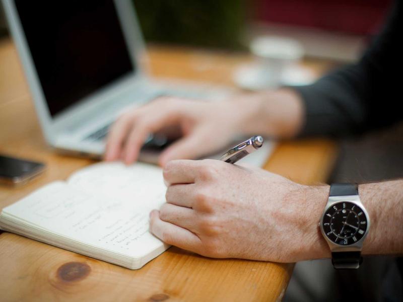 Beraterin notiert Kennzahlen neben aufgeklapptem Notebook