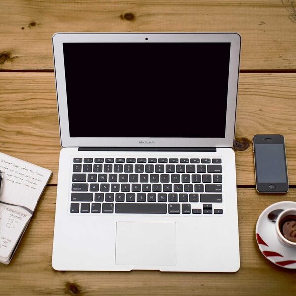 Notebook, Notizbuch und Kaffee auf einem Holztisch