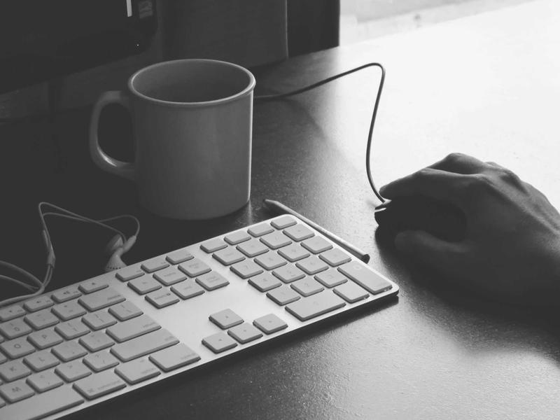Schwarzweißaufnahme von Tastatur, Maus und Kaffeebecher