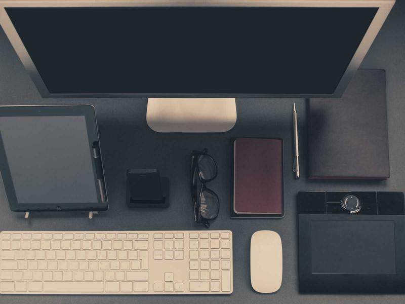 Flatlay mit Monitor, Tastatur und Arbeitsgeräten